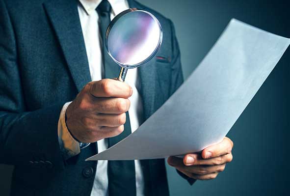 Resource Center Feature Businessman looking for information under magnifying glass.